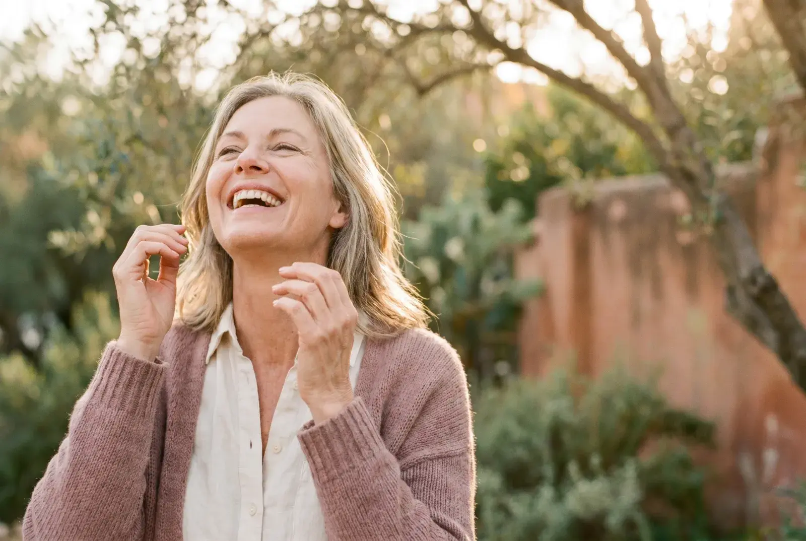 A woman laughing freely outdoors in golden sunlight